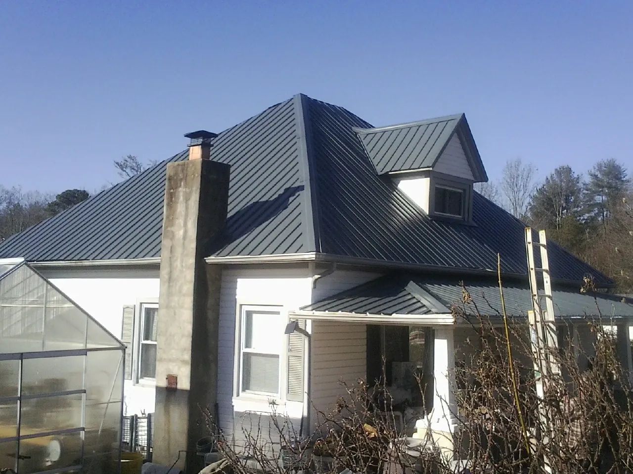 Dark blue standing seam metal roof on a white farmhouse with dormer — Slate & Tile Roof Repair by Roofing Brothers in Hartselle