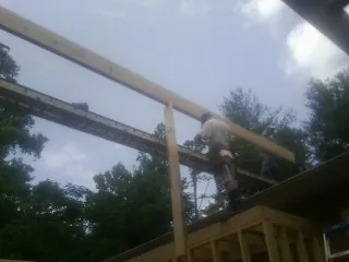Carpenter setting a ridge beam over a new addition frame — Ice Dam Removal by Roofing Brothers in Hartselle