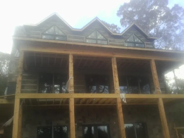Dormers and porch framing on a large log home under construction — Roof Coating work by our crew in Hartselle