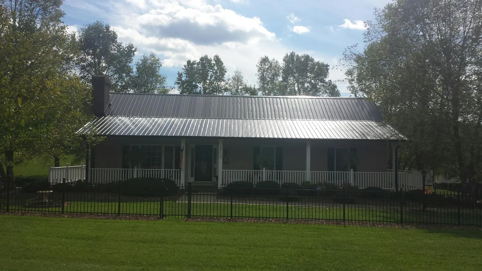 Gray metal roof on a brick ranch with a full width front porch — Gutter Guard Installation work by our crew in Hartselle