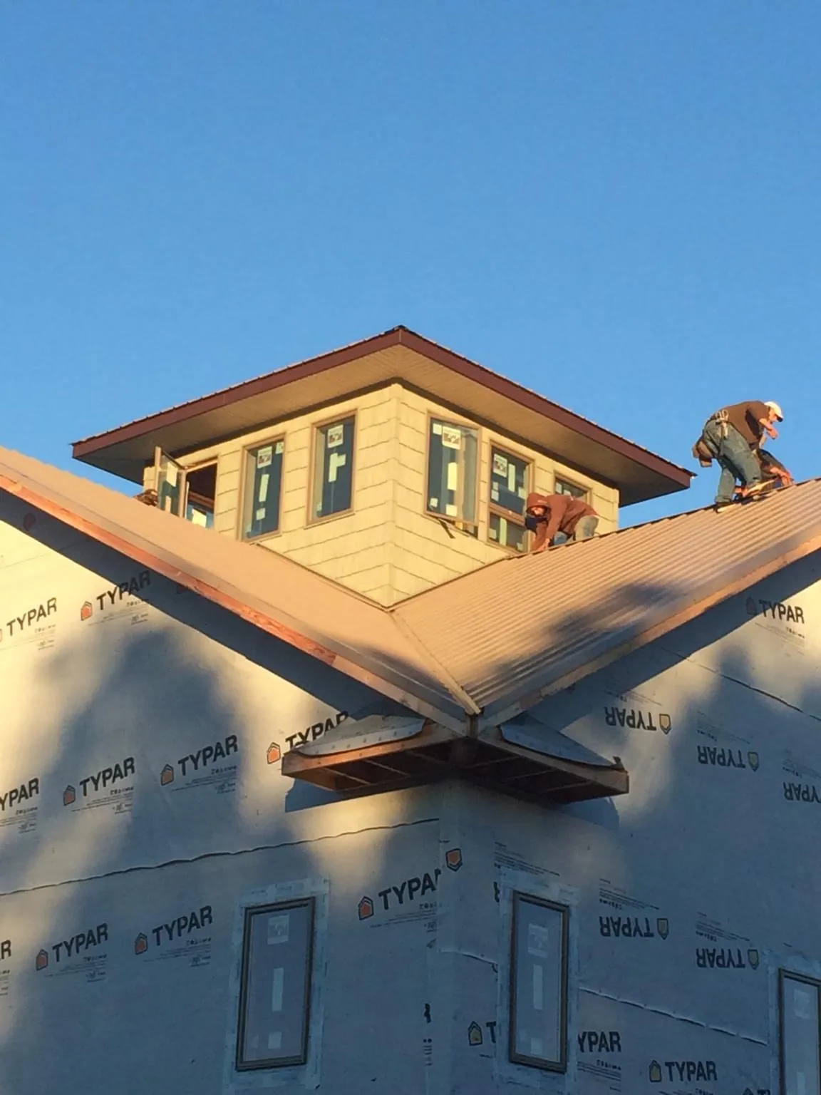 Roofers working around a rooftop cupola on a new metal roof at sunset — Roof Waterproofing in Hartselle by Roofing Brothers